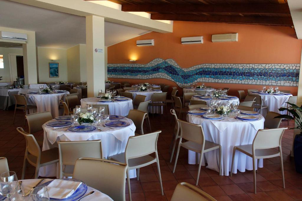 une salle à manger avec des tables et des chaises blanches dans l'établissement Hotel Residence La Darsena, à Agropoli