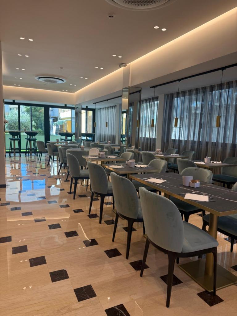 une salle à manger avec tables, chaises et fenêtres dans l'établissement Hotel Grazia Riccione, à Riccione