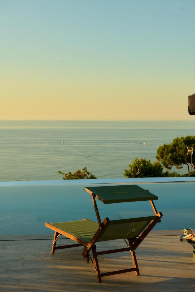 une chaise verte assise sur une terrasse avec vue sur l'océan dans l'établissement Hidden Dalla Gioconda, à Gabicce Mare