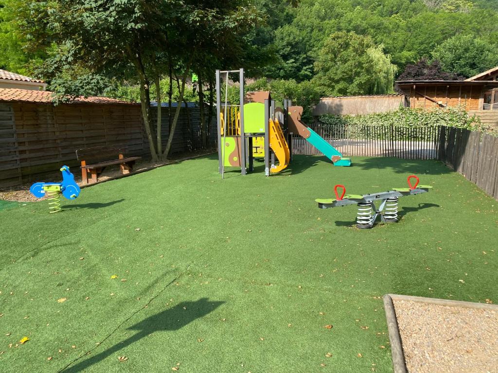 une cour arrière avec une aire de jeux avec des équipements de jeux sur l'herbe dans l'établissement Camping les Sables, à Tournon-sur-Rhône