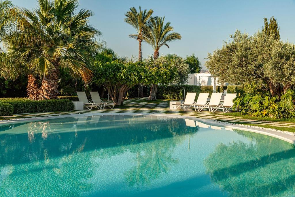 une piscine avec chaises longues et palmiers dans l'établissement Il Giardino degli Dei, à San Leone