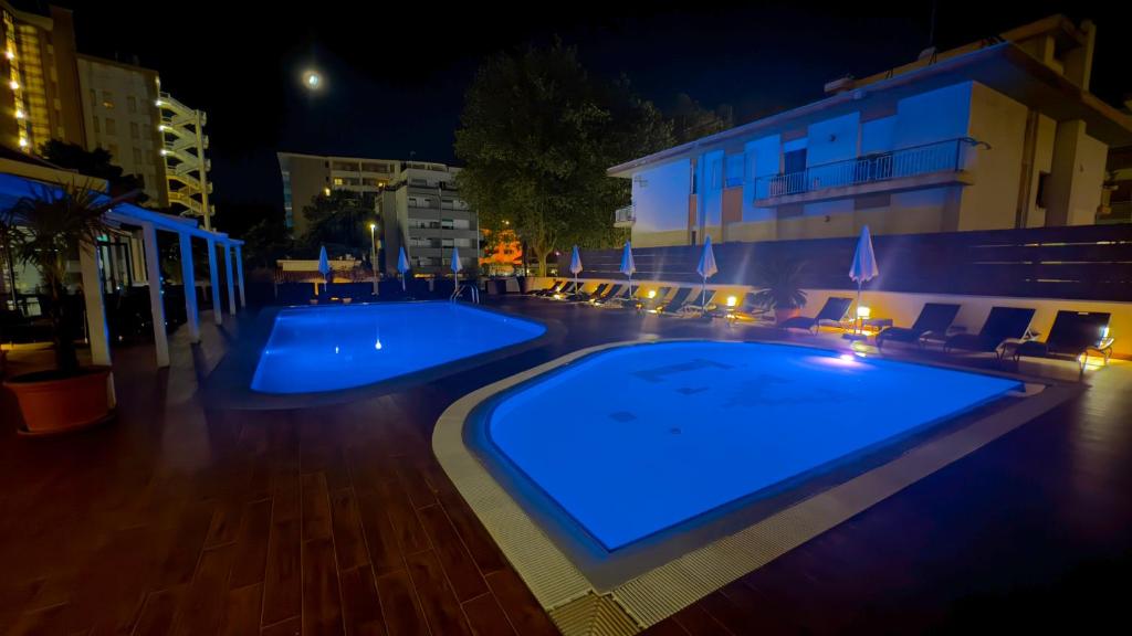 - une piscine avec un hôtel la nuit dans l'établissement Hotel Leonardo Da Vinci Wellness SPA, à Bibione