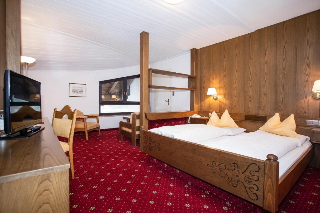 une chambre d'hôtel avec un lit et une télévision dans l'établissement Hotel Am Wolfgrubenersee, à Soprabolzano