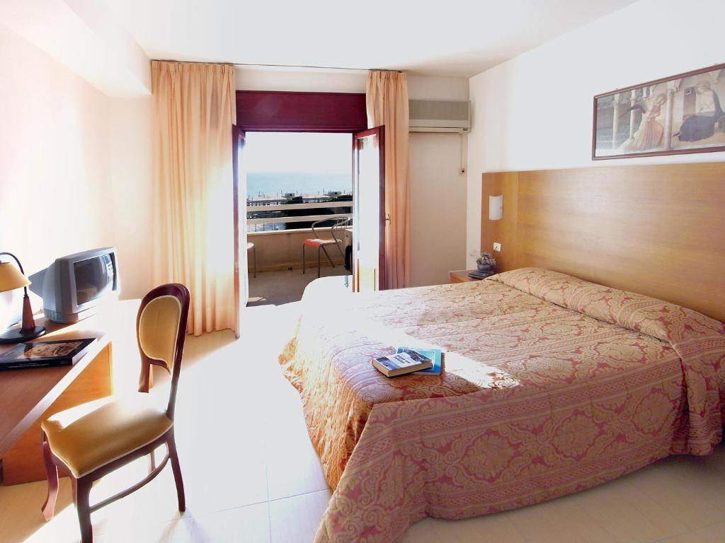 une chambre d'hôtel avec un lit, un bureau et une télévision dans l'établissement Hotel Alceste, à Marinella di Selinunte