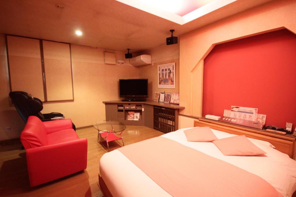 une chambre avec un lit et un mur rouge dans l'établissement マイルームーmy roomー,