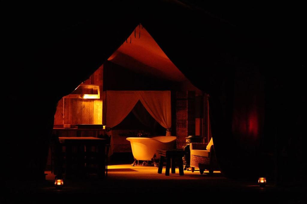 Cette chambre sombre comprend une tente avec des chaises et des lumières. dans l'établissement Kimaro Farmhouse, à Colméry