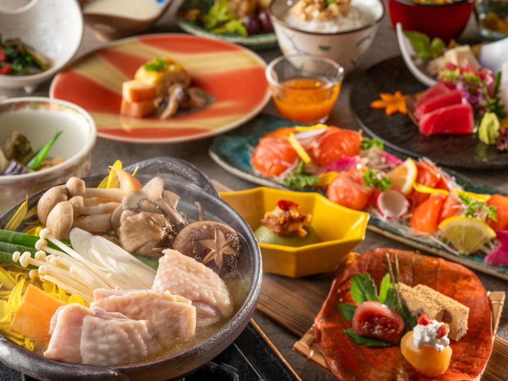 une table avec de nombreuses assiettes de nourriture dessus dans l'établissement KAMENOI HOTEL Kitsuregawa, à Sakura