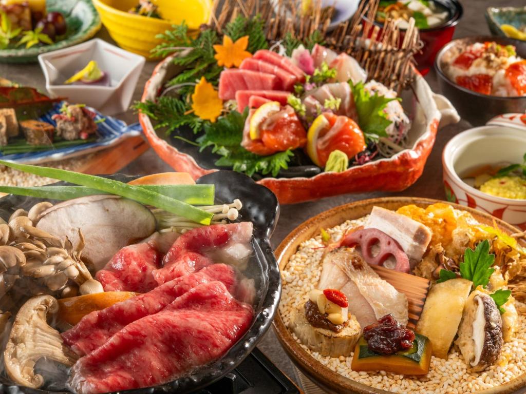 une table remplie de différents types de denrées alimentaires sur les assiettes dans l'établissement KAMENOI HOTEL Kitsuregawa, à Sakura