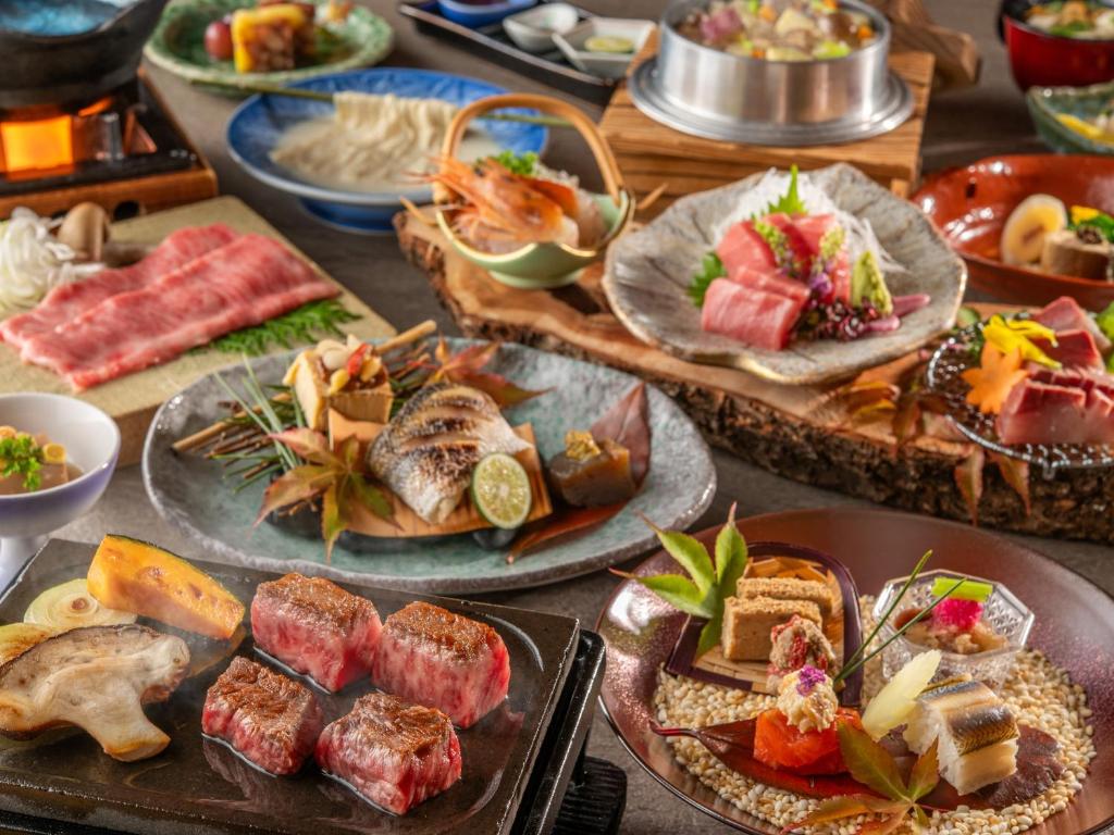 une table avec de nombreuses assiettes de nourriture dessus dans l'établissement KAMENOI HOTEL Kitsuregawa, à Sakura