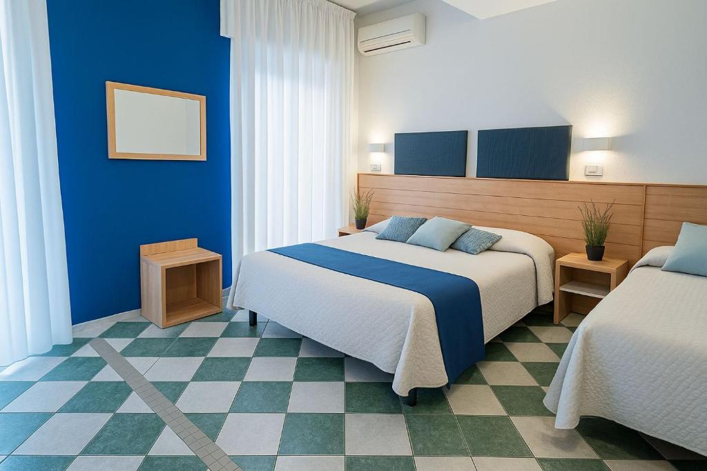 - une chambre d'hôtel avec 2 lits et des murs bleus dans l'établissement Hotel Aldebaran, à Rimini