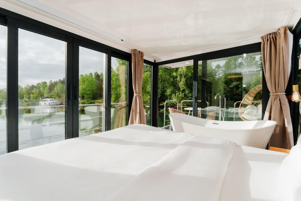 - une chambre avec un lit blanc et de grandes fenêtres dans l'établissement L'Escale Royale Saint-Fargeau-Ponthierry - Seine - Melun, à Boissise-le-Roi
