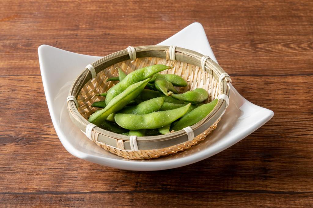 un panier de haricots verts sur une assiette sur une table dans l'établissement ホテルハンズ, à Ginan