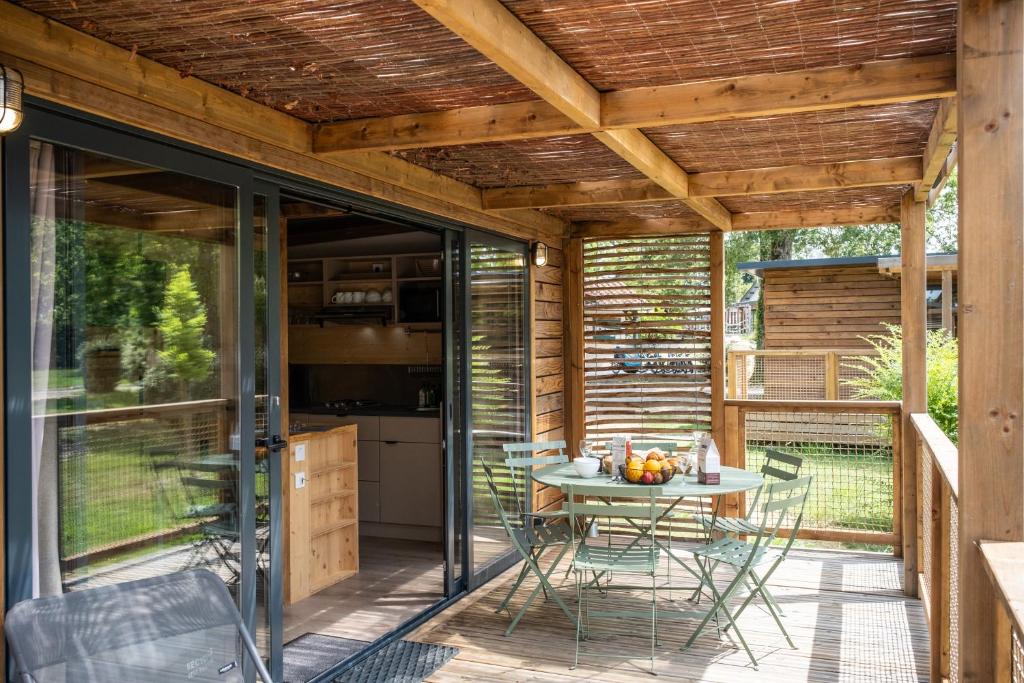 un patio avec une table et des chaises sur une terrasse dans l'établissement Huttopia Lac d'Aureilhan - Mimizan, à Aureilhan