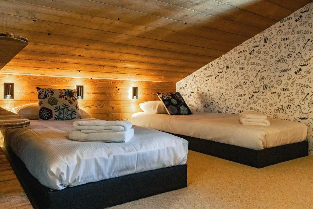 deux lits dans une chambre aux murs en bois dans l'établissement CHALET TEKA LES GETS - Appartement Chavannes, aux Gets