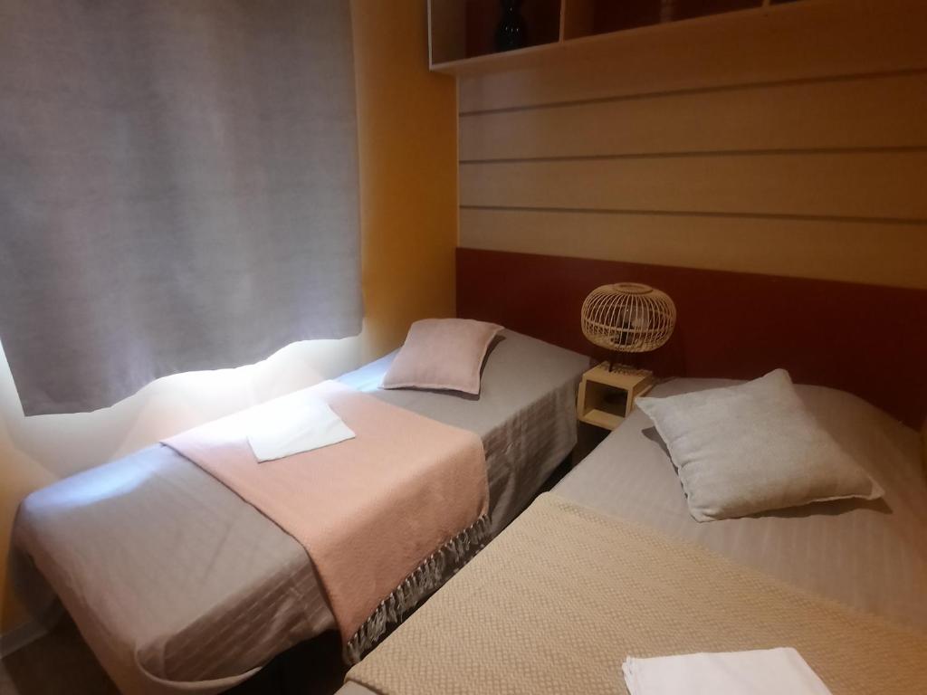 Cette chambre comprend deux lits et un ventilateur. dans l'établissement Camping Domaine des iscles, à La Roque-dʼAnthéron