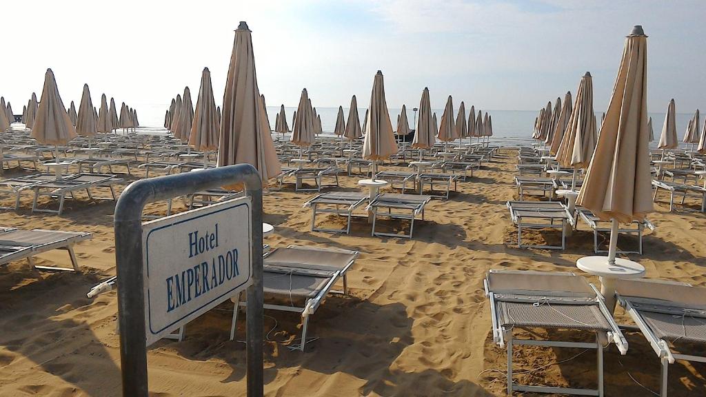 une plage avec des chaises et des parasols sur le sable dans l'établissement Hotel Emperador, à Lido di Jesolo