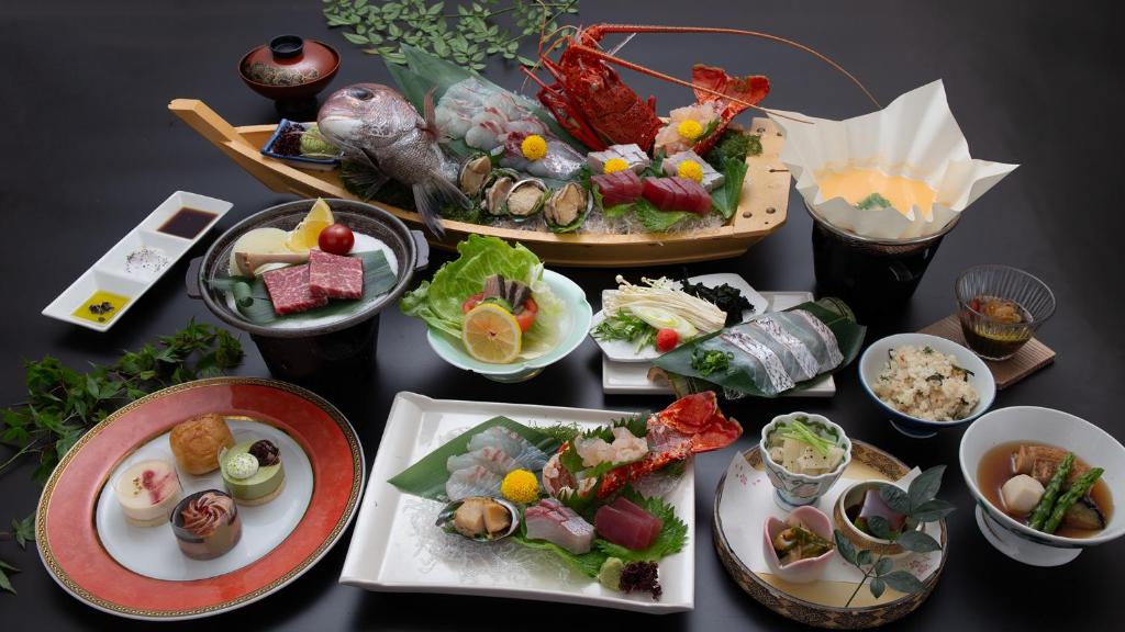 une table avec de nombreuses assiettes de nourriture dessus dans l'établissement Tenku Hotel Kairo, à Tonosho