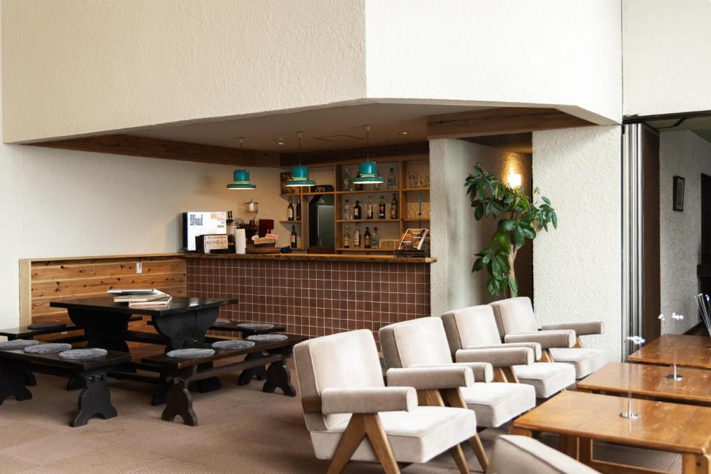 un restaurant avec des chaises blanches, une table et un comptoir dans l'établissement Kogakuro, à Myōkō