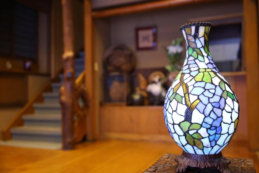 un vase en verre teinté posé sur une table dans l'établissement Ikariya Ryokan, à Yamanouchi