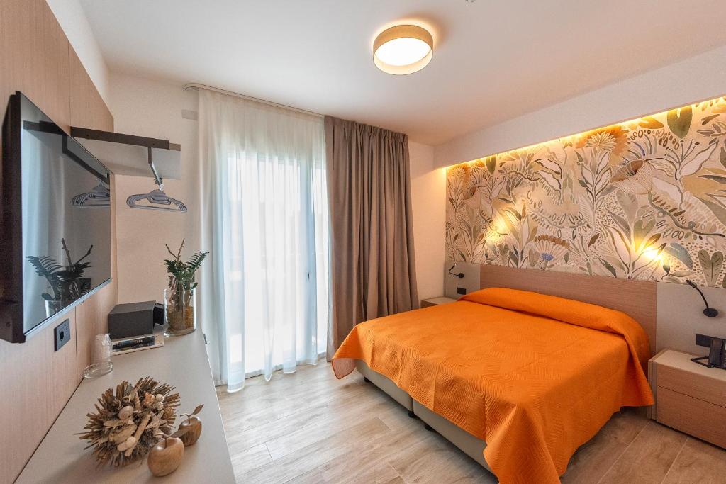 une chambre avec un lit avec une couverture orange dans l'établissement Hotel Golf ***S, à Bibione