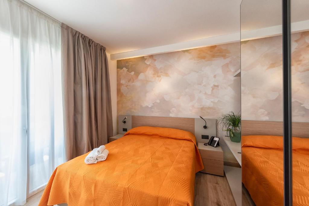 - une chambre avec 2 lits avec des draps orange dans l'établissement Hotel Golf ***S, à Bibione
