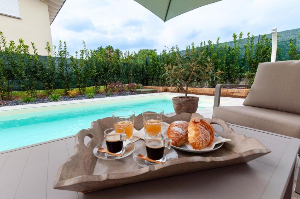 - un plateau de petit-déjeuner sur une table à côté de la piscine dans l'établissement Villa Melodica, à Carzago della Riviera