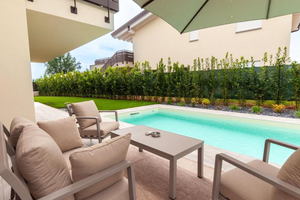 un patio avec une table et des chaises et une piscine dans l'établissement Villa Melodica, à Carzago della Riviera 81 autres photos