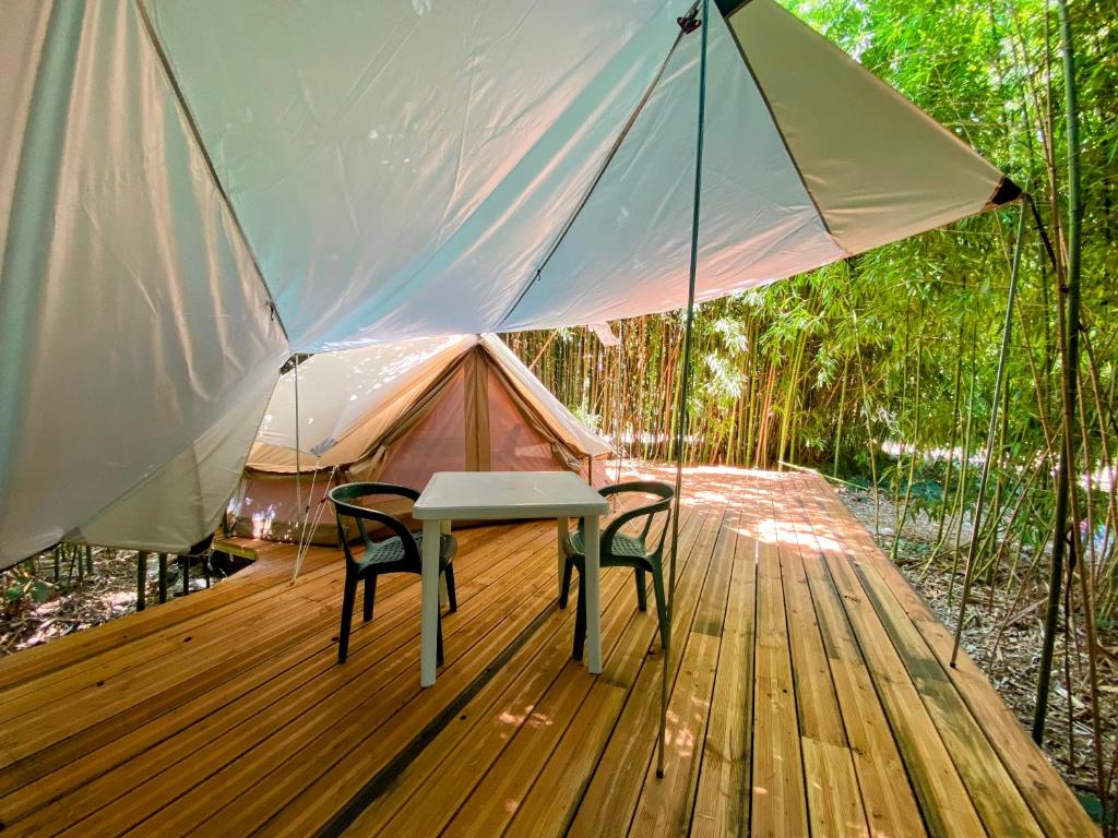 une table et des chaises sur une terrasse en bois avec une tente dans l'établissement Camping les Avenières, à Manthes 37 autres photos
