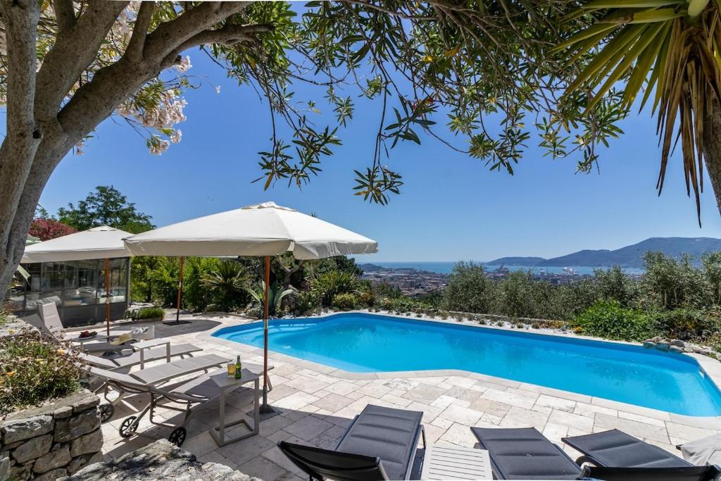 une piscine avec des chaises et un parasol dans l'établissement Villa Amaranta, à La Spezia