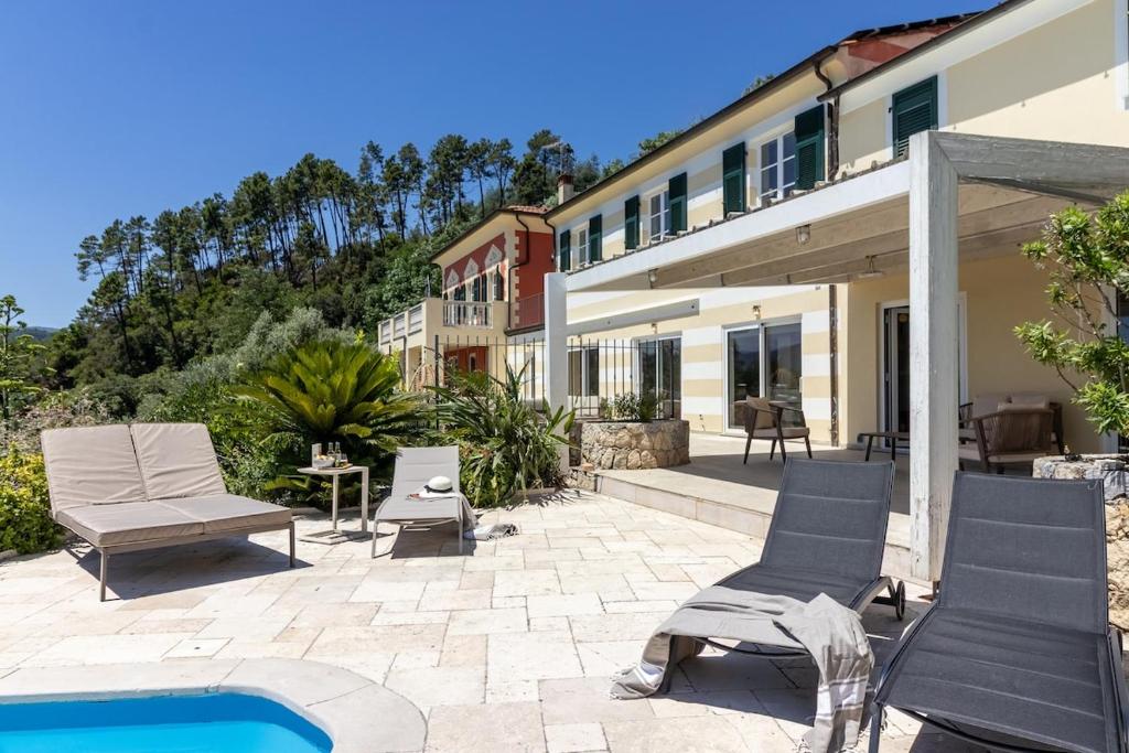 un patio avec des chaises et une piscine à côté d'un bâtiment dans l'établissement Villa Amaranta, à La Spezia