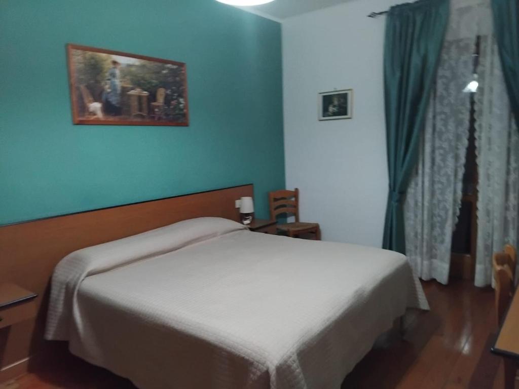 une chambre avec un lit blanc et un mur bleu dans l'établissement Hotel Turano, à Castel di Tora