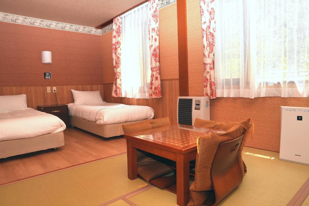 Cette chambre comprend deux lits, un bureau et une table. dans l'établissement Manor House, à Yamanakako