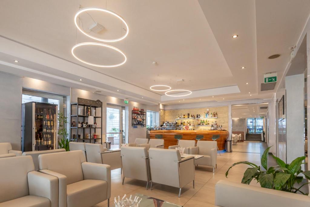 un restaurant avec des chaises blanches et un bar dans l'établissement Club Hotel, à Riccione