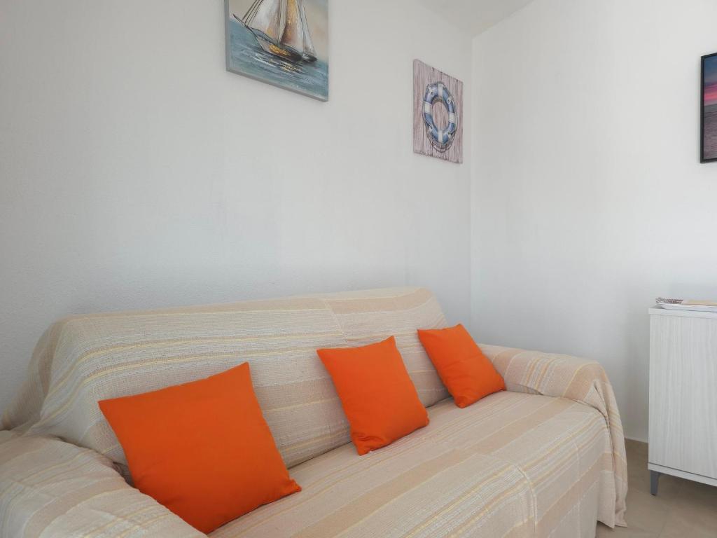 un canapé blanc avec deux coussins orange dessus dans l'établissement Villetta Lucy - Budoni Sweet Home, à Tanaunella