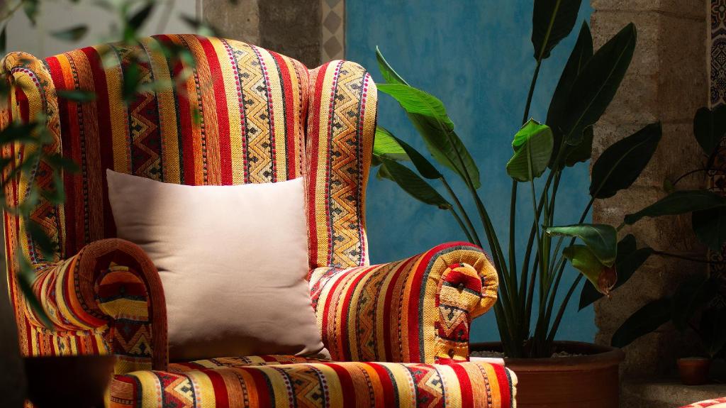 une chaise rouge avec un coussin blanc et une plante dans l'établissement Riad Al Manara, à Essaouira