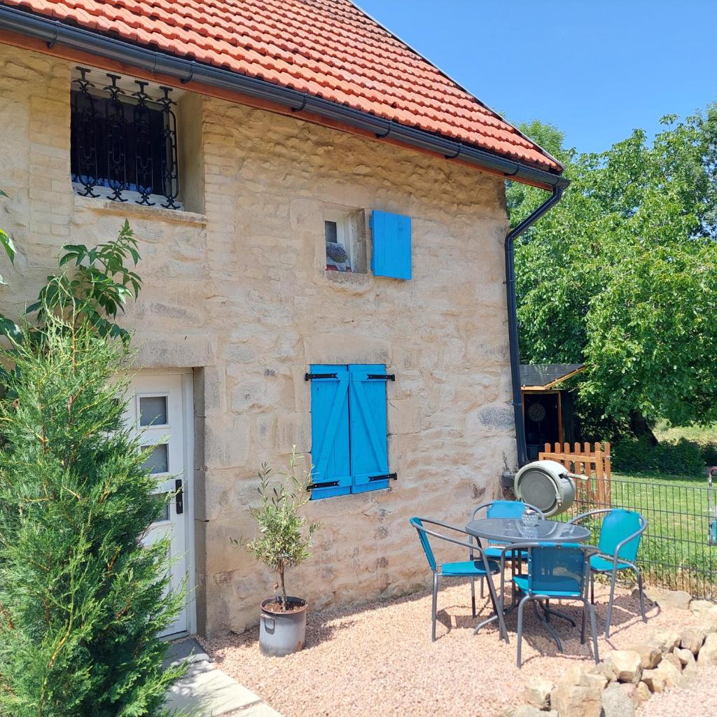 une table et des chaises devant une maison avec portes bleues dans l'établissement Gite Charassat, à Saint-Marcel-en-Marcillat