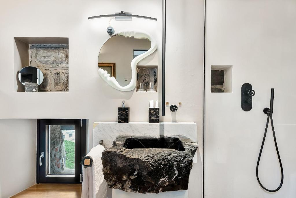 une salle de bain avec un lavabo et un miroir au mur dans l'établissement Capitolare Suite Tower, à Portovenere