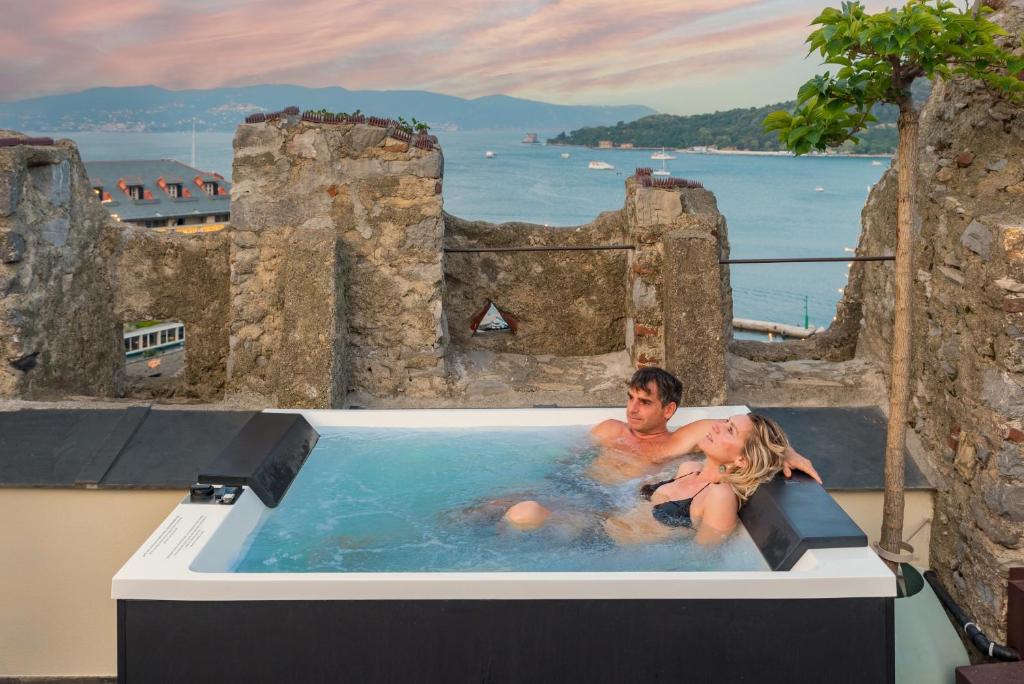 un homme et une femme assis dans un jacuzzi dans une baignoire de château dans l'établissement Capitolare Suite Tower, à Portovenere