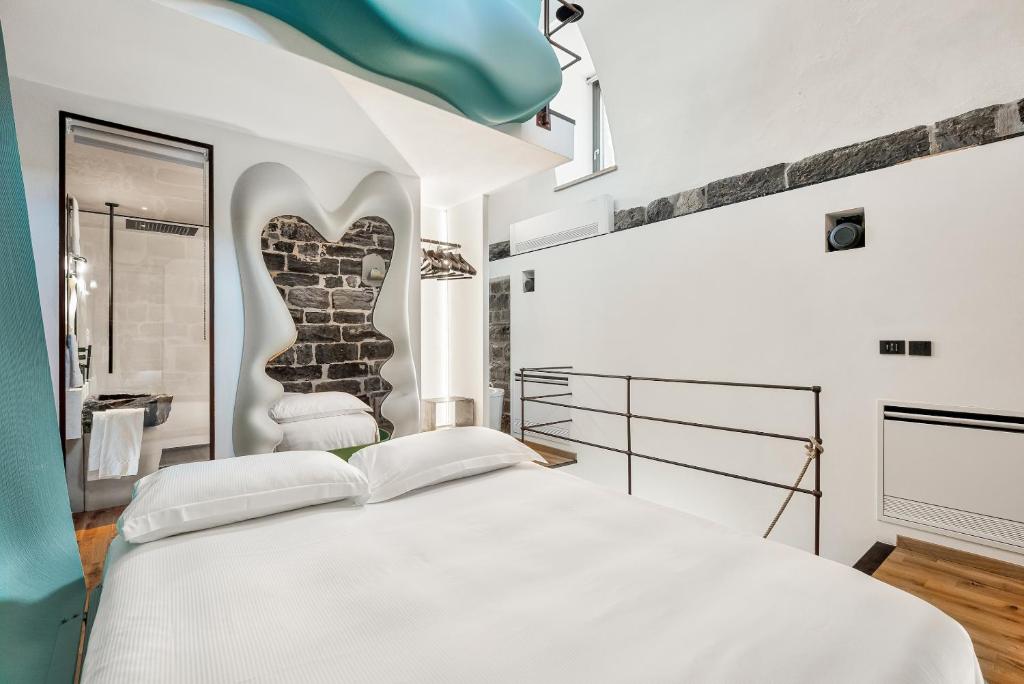 une chambre avec un grand lit blanc et un miroir dans l'établissement Capitolare Suite Tower, à Portovenere