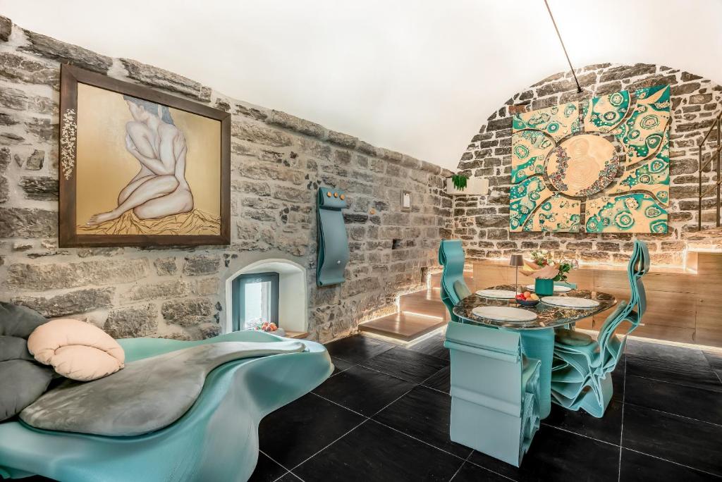 Cette chambre est dotée d'un mur en pierre, d'une table et de chaises. dans l'établissement Capitolare Suite Tower, à Portovenere