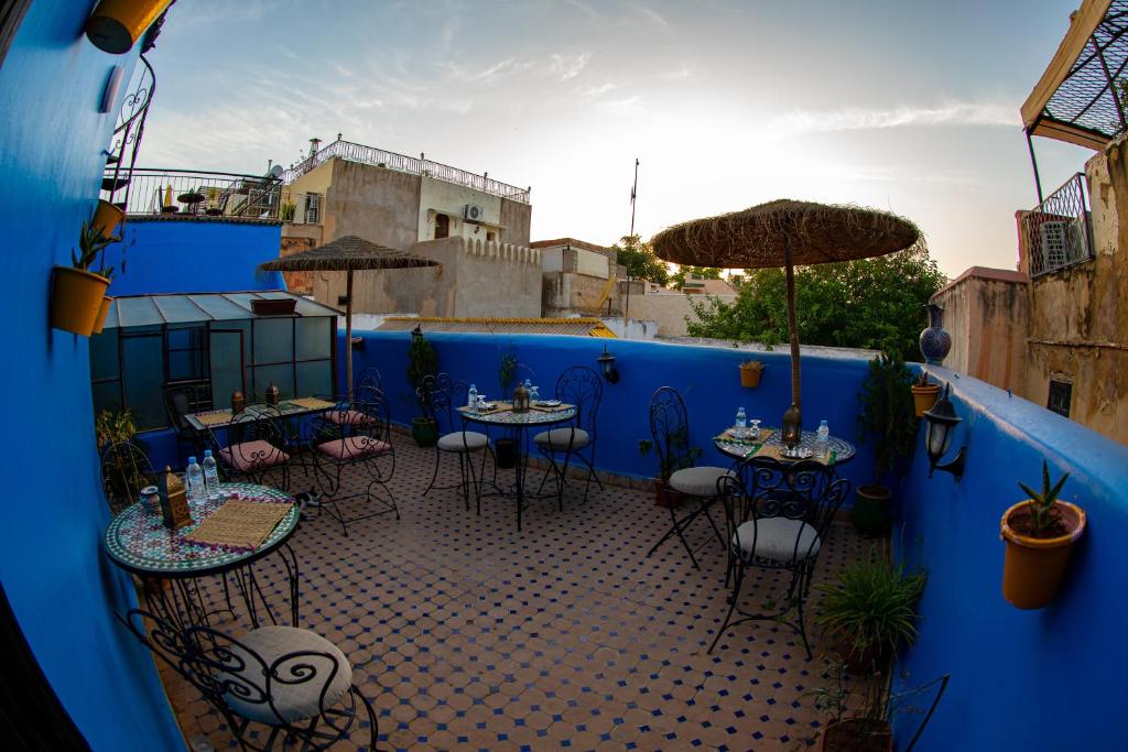 un patio avec des tables et des chaises et un mur bleu dans l'établissement Riad LalaMoune, à Fès