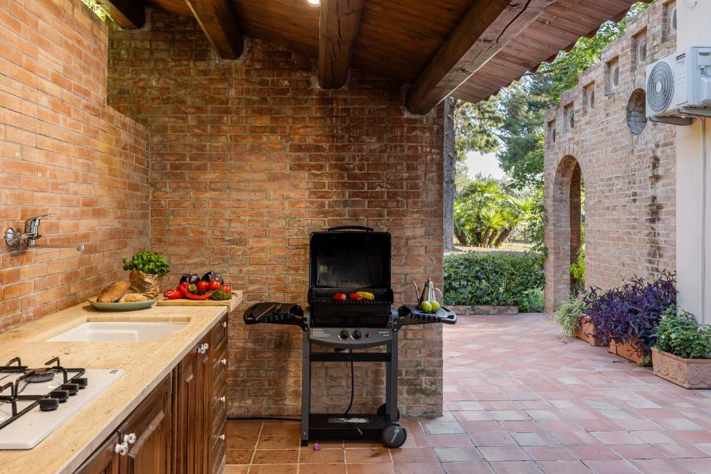 une cuisine extérieure avec un grill dans un mur de briques dans l'établissement Cleo - Villa Siciliana, à Partinico