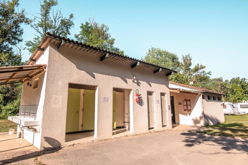une petite maison avec des portes vertes et une cour dans l'établissement Camping Onlycamp De Chamarges, à Die