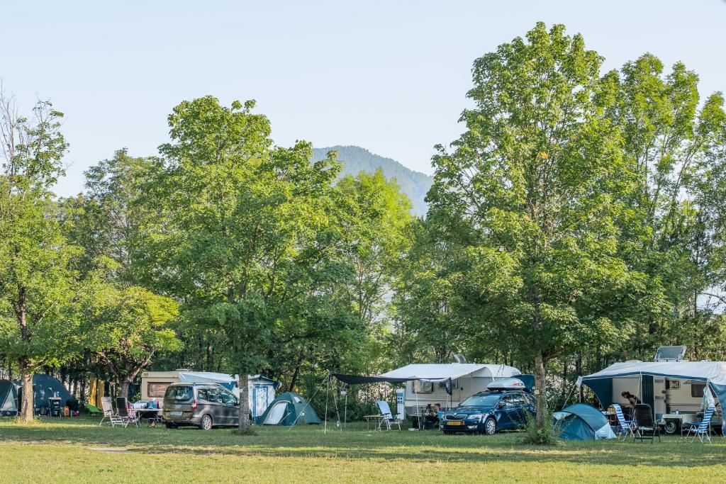 un groupe de tentes et de voitures garées dans un champ dans l'établissement Camping Onlycamp De Chamarges, à Die