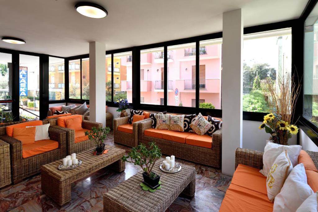 un salon avec des canapés, des tables et des fenêtres dans l'établissement Hotel Alaska, à Rimini