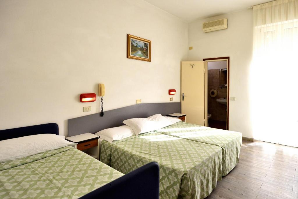Cette chambre d'hôtel comprend 2 lits avec des draps verts. dans l'établissement Hotel Alaska, à Rimini