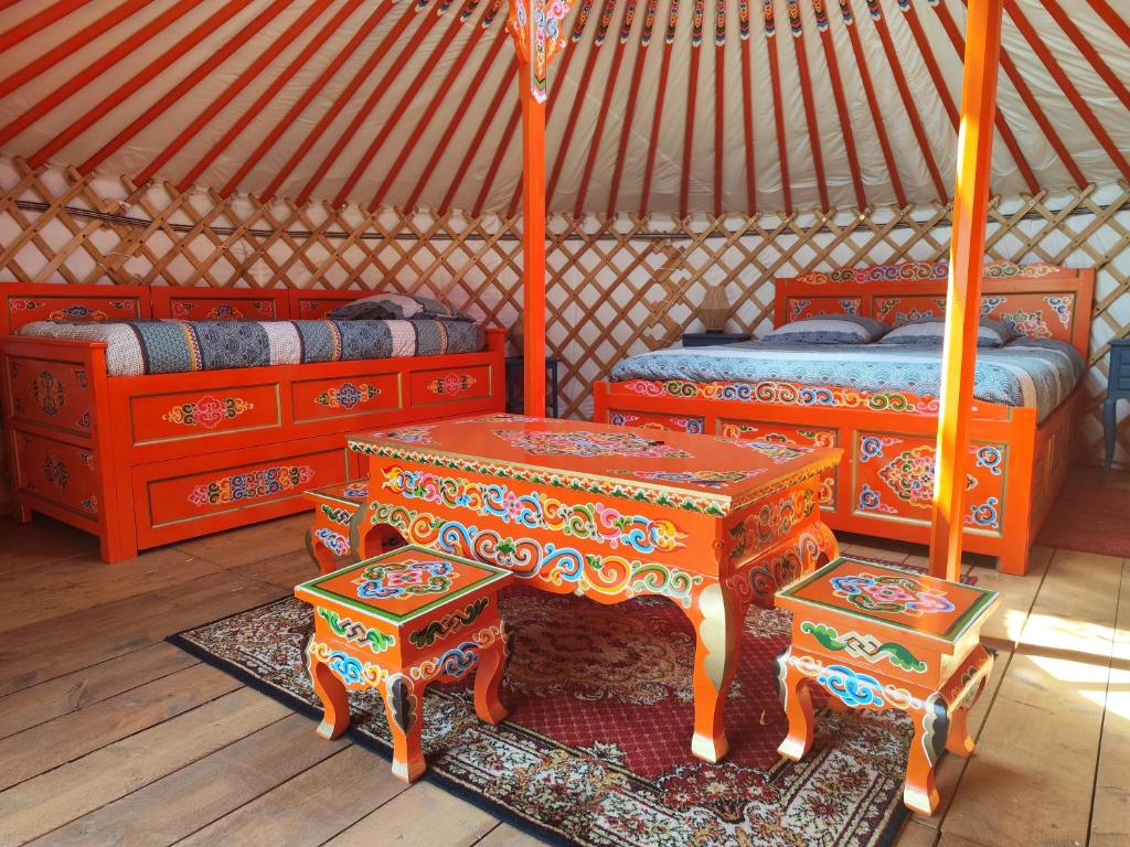 une chambre avec deux lits et des tables dans une yourte dans l'établissement Yourte traditionnelle mongole, à Marcoux