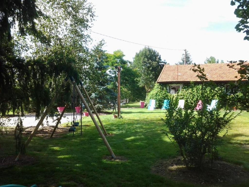 - une balançoire dans une cour avec une maison dans l'établissement Maison rénovée avec parc, piscine partagée et activités pour enfants - Draps et linge offerts - FR-1-489-324, à Moulins 7 autres photos
