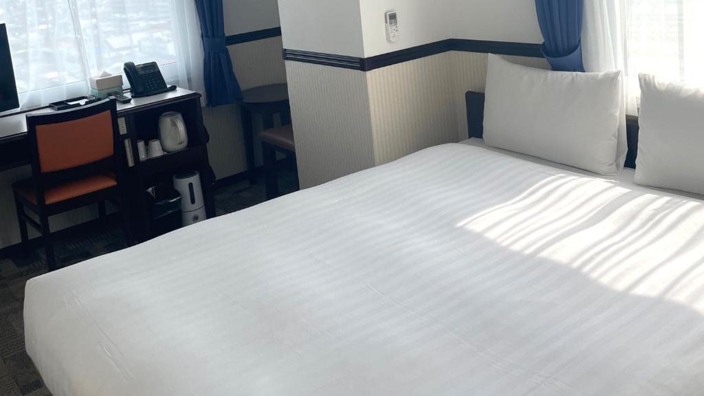 un grand lit blanc dans une chambre avec une fenêtre dans l'établissement Toyoko Inn Saitama Iwatsuki Ekimae, à Saitama