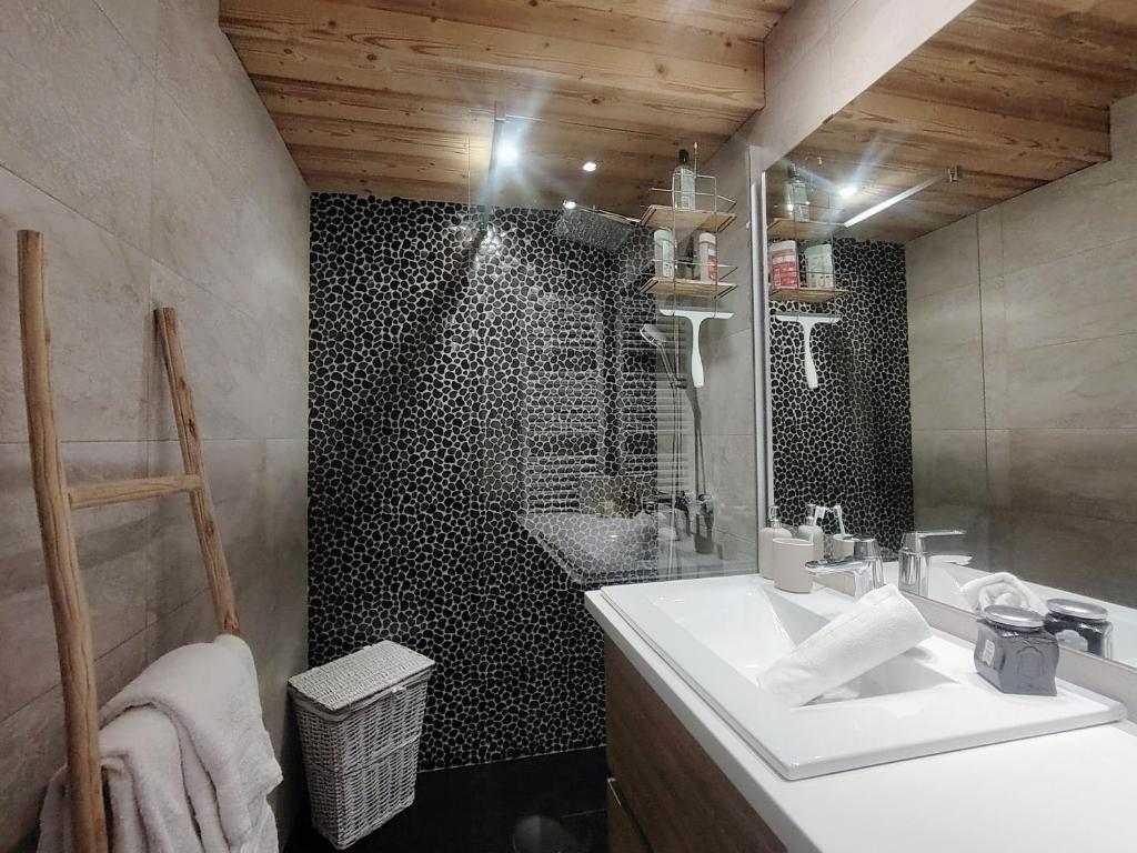 La salle de bains est pourvue d'un lavabo blanc et d'un mur en carrelage noir. dans l'établissement Homency - Résidence Les Gémeaux A5, à L'Alpe-d'Huez 13 autres photos